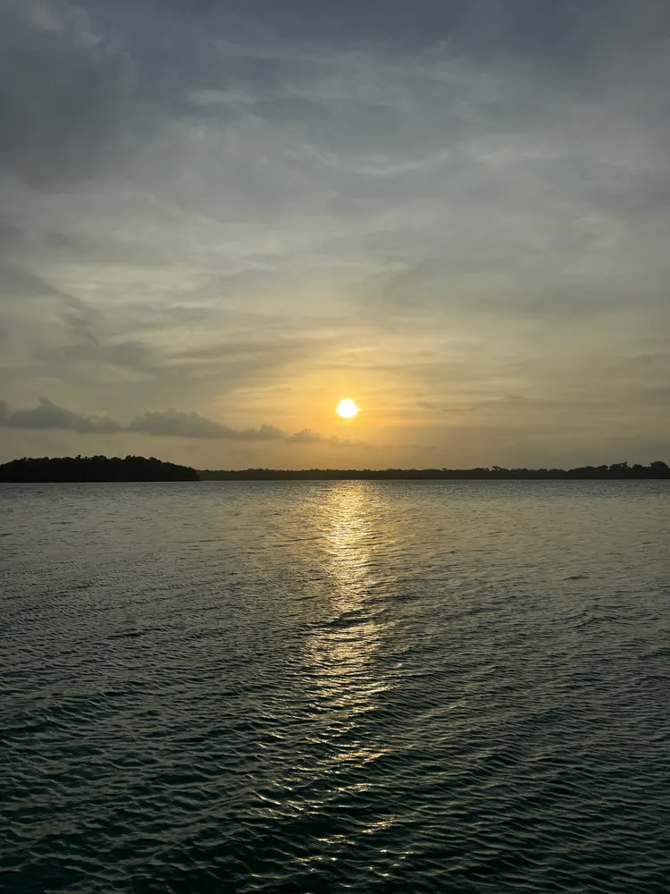 Sunset over a lagoon, with a strip of shore on the horizon