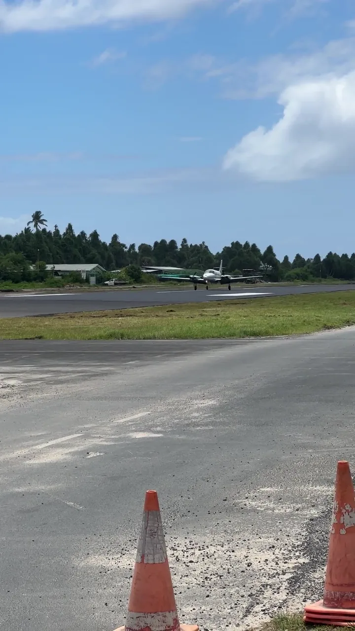 A plane on the Funafuti runway. Low buildings of the atoll stand around it.
